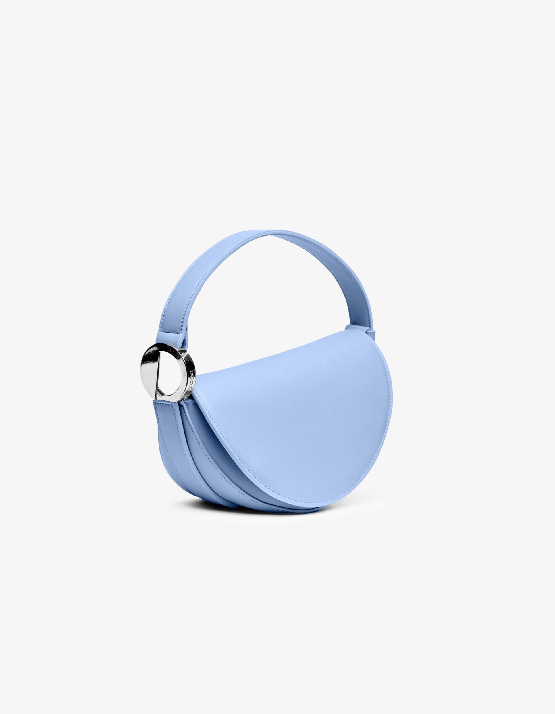 A blue handbag with a semi-circular shape and a metallic hardware piece on the strap, set against a plain background.
