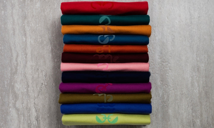 Stack of rainbow Dooz Knit Tees in for twelve zodiac signs
